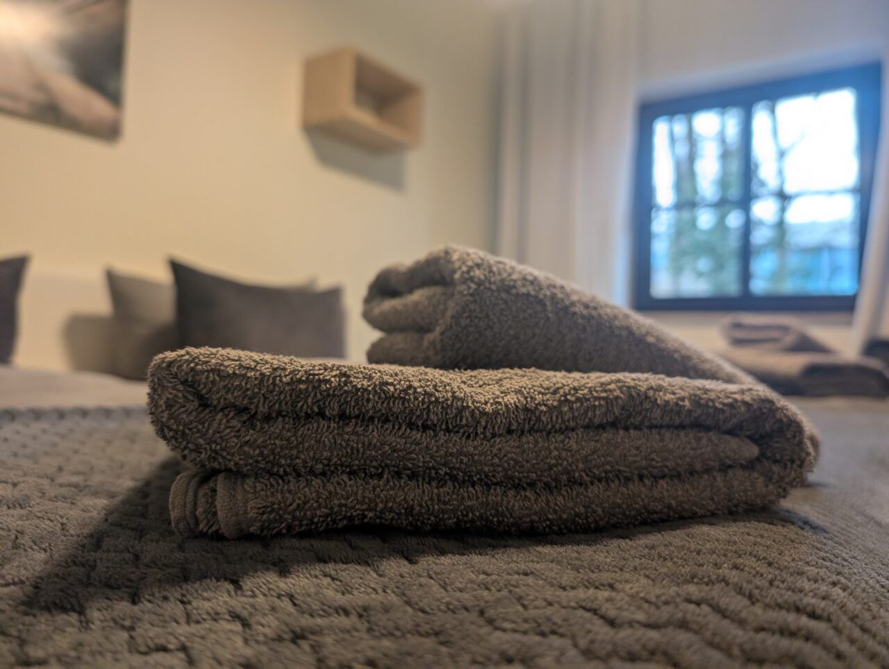 Gefaltete Handtücher auf dem Bett, Blick zum Fenster
