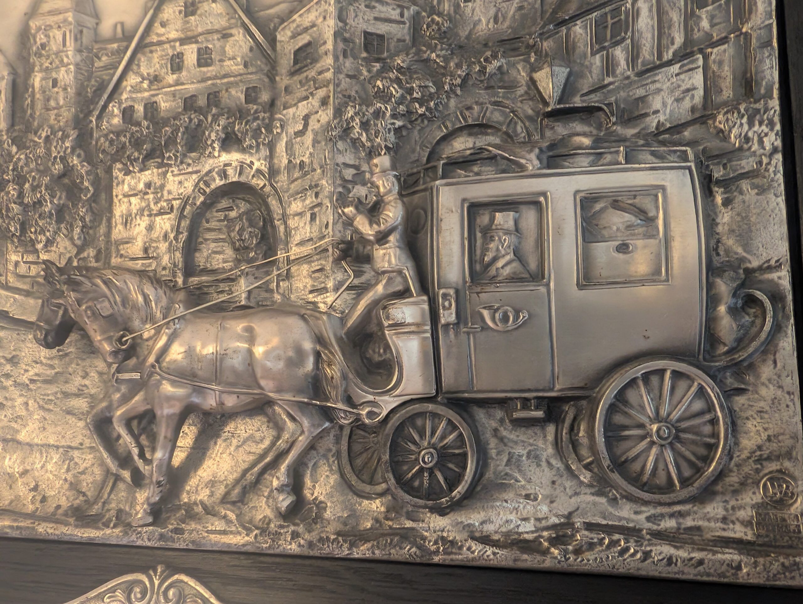 Silbernes Relief einer historischen Postkutsche mit Pferden